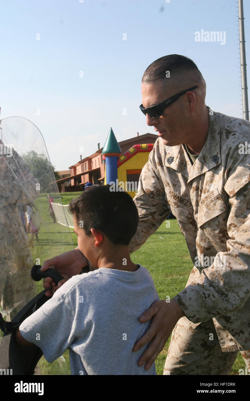 Gunnery Sgt. Francisco Alvarez, a motor transport chief with Special-Purpose Marine Air-Ground Task Force Africa 13, demonstrates the capabilities of several non-lethal weapons to a local child at the National Night Out event aboard Naval Air Station Sigonella, Italy, Aug. 6, 2013. Marines and sailors with Special-Purpose MAGTF Africa participated in the event with a static display of weapons, both lethal and non-lethal. Special-Purpose MAGTF Africa continues to build relationships with the community while simultaneously strengthening U.S. Africa Command and U.S. Marine Corps Forces Africa's a Stock Photo