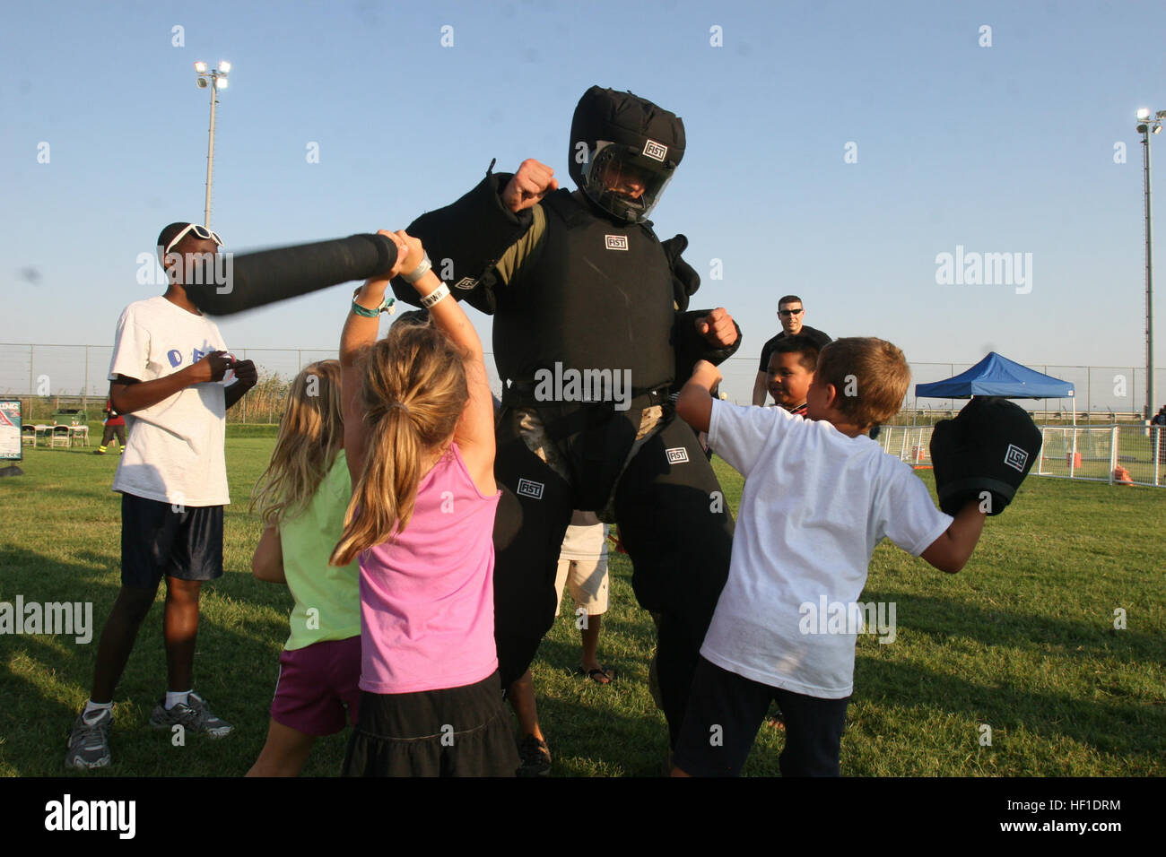 Purpose Marine-Air Ground Task Force Africa 13, demonstrates the resilience of riot gear while children strike him with batons at the National Night Out event aboard Naval Air Station Sigonella, Italy, Aug. 6, 2013. Marines and sailors with Special-Purpose MAGTF Africa participated in the event with a static display of weapons, both lethal and non-lethal. Special-Purpose MAGTF Africa continues to build relationships with the community while simultaneously strengthening U.S. Africa Command and U.S. Marine Corps Forces Africa's ability to assist partner nations in addressing security challenges  Stock Photo