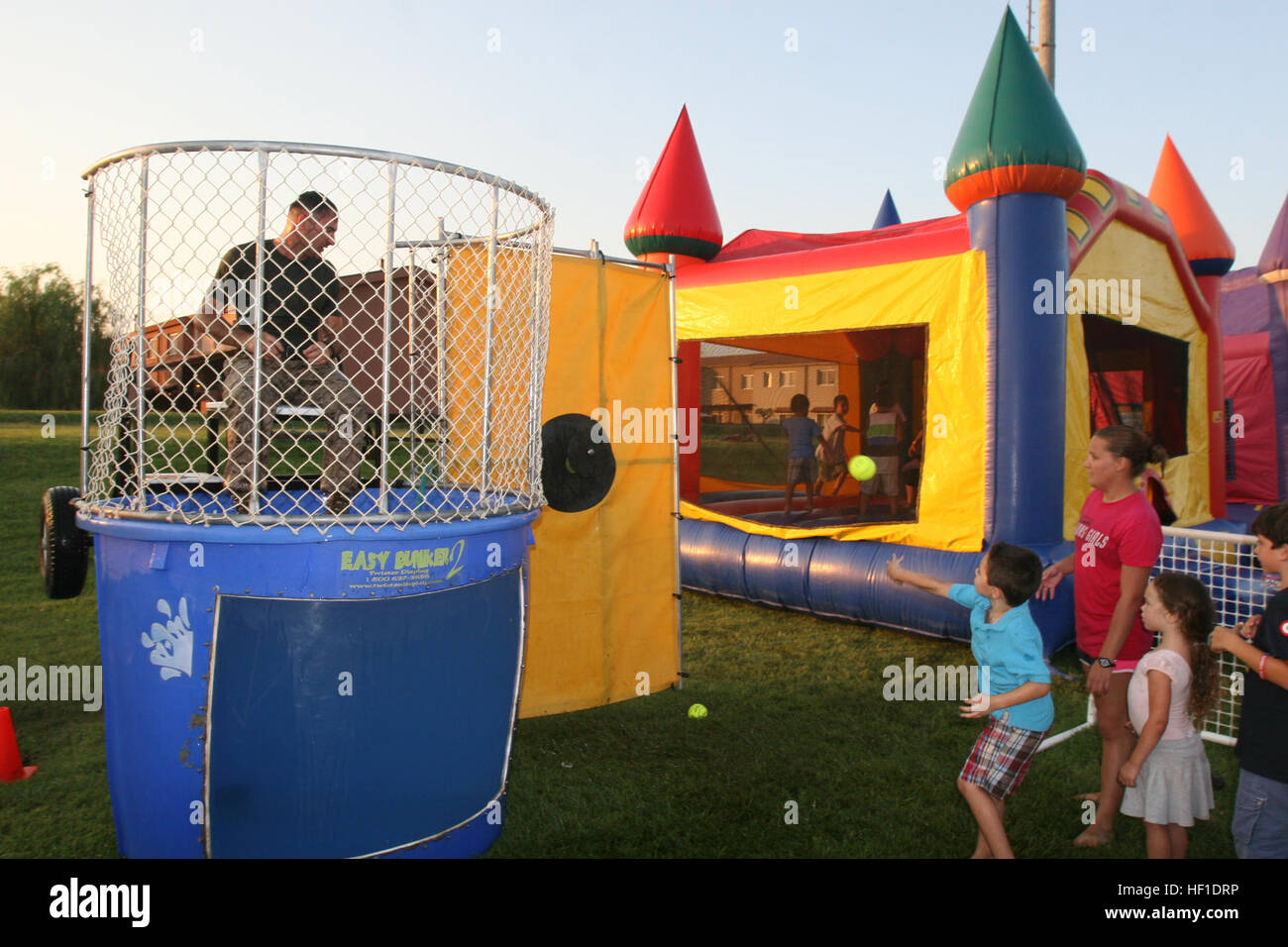 Sgt. Michael Stanley, an ammunitions technician specialist with Special-Purpose Marine-Air Ground Task Force Africa 13, awaits being dunked as children throw softballs attempting to hit the target at the National Night Out event aboard Naval Air Station Sigonella, Italy, Aug. 6, 2013. Marines and sailors with Special-Purpose MAGTF Africa participated in the event with a static display of weapons, both lethal and non-lethal. The task force continues to build relations with the community while simultaneously strengthening U.S. Marine Corps Forces Africa and U.S. Africa Command's ability to assis Stock Photo