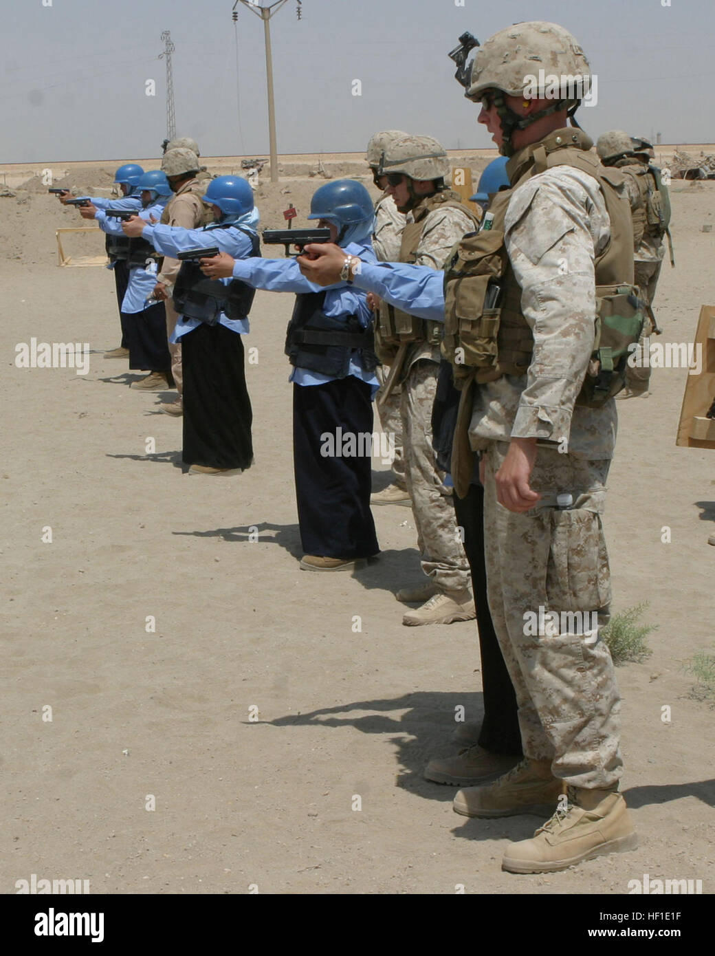 U.S. Marine Cpl. Roberts, 2nd Battalion, 5th Marines [2-5], 3rd Infantry Division, II Marine Expeditionary Force, coaches a female police officer during dry fire drills at the pistol range Joint Security Station Iron in Al Ramadi, Iraq, July 28. The female officers are being trained by fellow police officers of South Ramadi and U.S. Marines with 2nd Battalion, 5th Marines [2-5], 3rd Infantry Division, II Marine Expeditionary Force. The unit is deployed with Multi-National Forces-West in support of Operation Iraqi Freedom in the Al Anbar province of Iraq to develop Iraqi security forces, facili Stock Photo