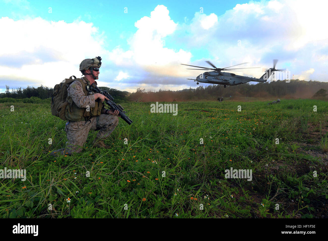 U.S. Marine Corps Cpl. Justin Bloomer, a squad leader with the 1st squadron, 81mm Platoon, TRAP Section, Weapons Company, Battalion Landing team 1/4, 13th Marine Expeditionary Unit, provides security while a CH-53E Super Stallion helicopter lands in the background to carry members of his team back to the USS Boxer (LHD-4) during Operation Tropic Thunder on the Island of Oahu, Hawaii, Aug. 31, 2013. (DoD photo by SSgt. Matt Orr, U.S. Marine Corps/Released) 130831-M-MC013-0388 (9688968782) Stock Photo