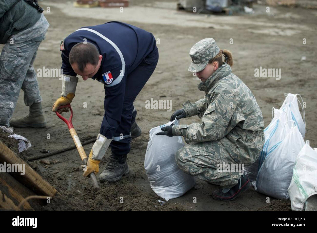 Second Lt. Christina Heino from Hydepark, N.Y., assigned to the 301st Intelligence Squadron, works alongside members of the French army to clean up a local road during a cleanup effort here in this tsunami-battered city. More than 130 volunteers from Misawa Air Base and members of the French army and Fire Department assisted in a cleanup effort in the northern Japanese city that was devastated by a 9.0-magnitude earthquake that triggered a devastating tsunami on Japan's eastern coastline. (U.S. Navy photo by Cryptologic Technician (Collection) 2nd Class Thomas Ahern/Released) Flickr - DVIDSHUB Stock Photo