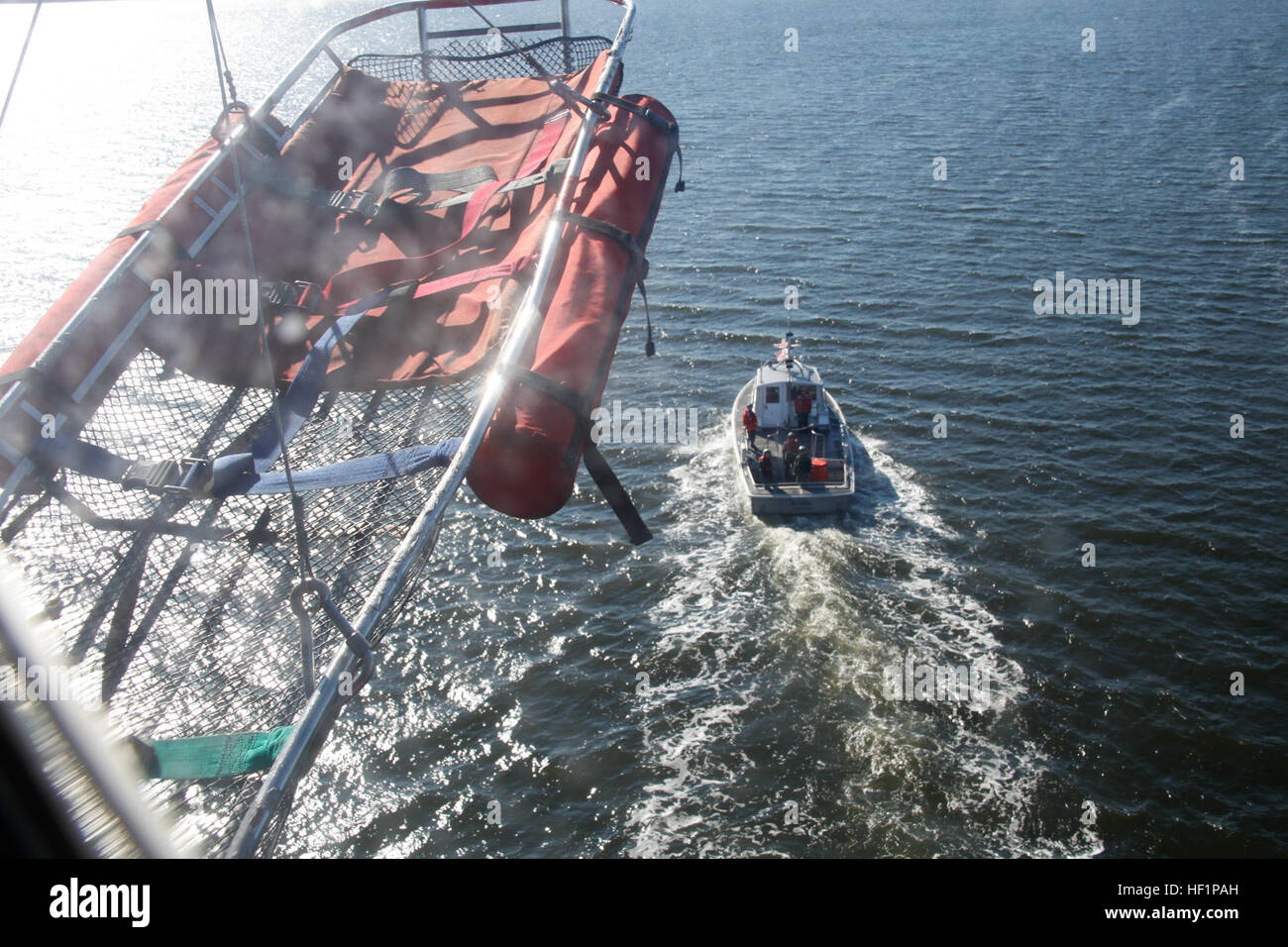 A Coast Guard utility boat conducts hoisting training with an HH46E