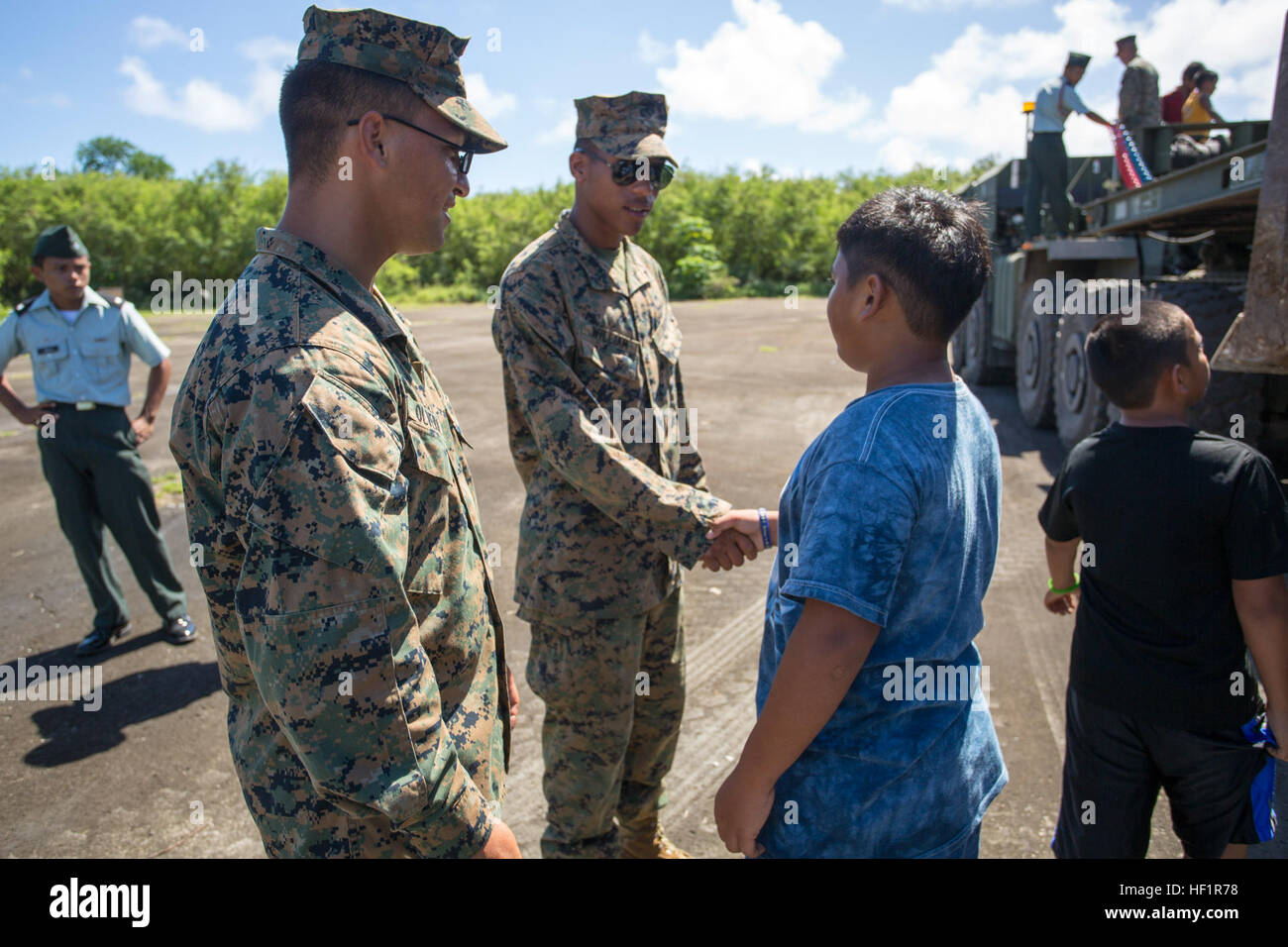 Lance Cpl. Raynaldo Olvera, from Dallas, TX., and Lance Cpl. Javan William, from the Virgin Islands, are thanked for their service by local Tinian children Nov. 11 after a Veterans Day and Marine Corps birthday ceremony at Tinian's Historic North Field during exercise Forager Fury II. Olvera and William showed the children the heavy equipment they operate and how exactly they will restore the air field. Olvera is a heavy equipment mechanic and William is a heavy equipment operator with Marine Wing Support Squadron 171, Marine Aircraft Group 12, 1st Marine Aircraft Wing, III Marine Expeditionar Stock Photo