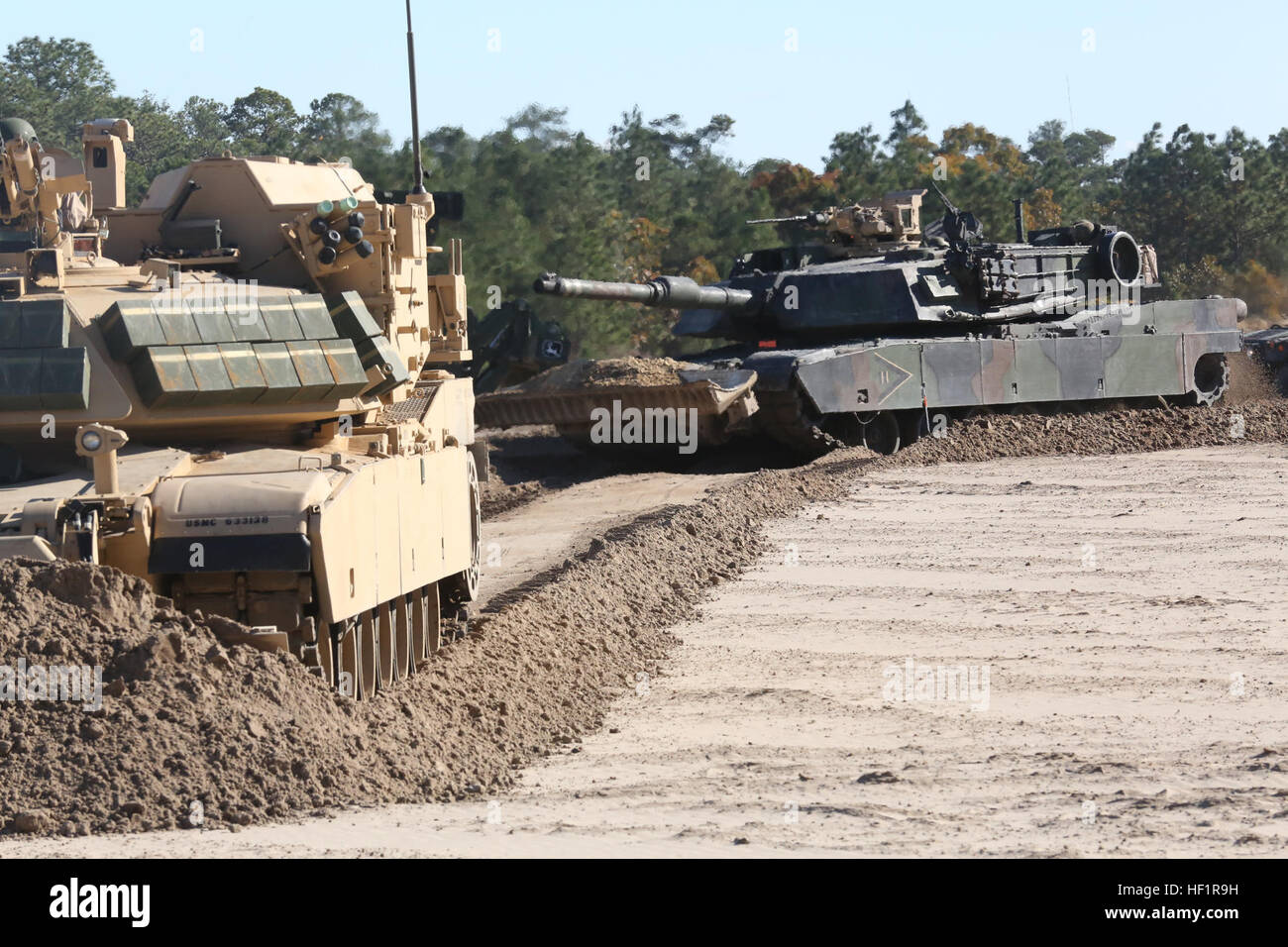 An M1 Abrahms Main Battle Tank follows an Assault Breacher Vehicle as