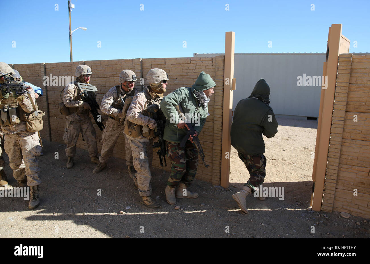 Marines with Bravo Company, 1st Battalion, 7th Marine Regiment, follow Afghan role-players into a compound during a counterinsurgency exercise on Range 220 at Marine Corps Air Ground Combat Center Twentynine Palms, Calif., Dec. 9, 2013. The $140 million urban warfare training facility consists of more than 1,000 buildings and is divided into four sectors. The buildings replicate what can be found in an urban town to include gas stations, factories, one story complexes, marketplaces and multiple story buildings. Infantrymen work hand in hand with Afghans during counterinsurgency exercise 131209 Stock Photo