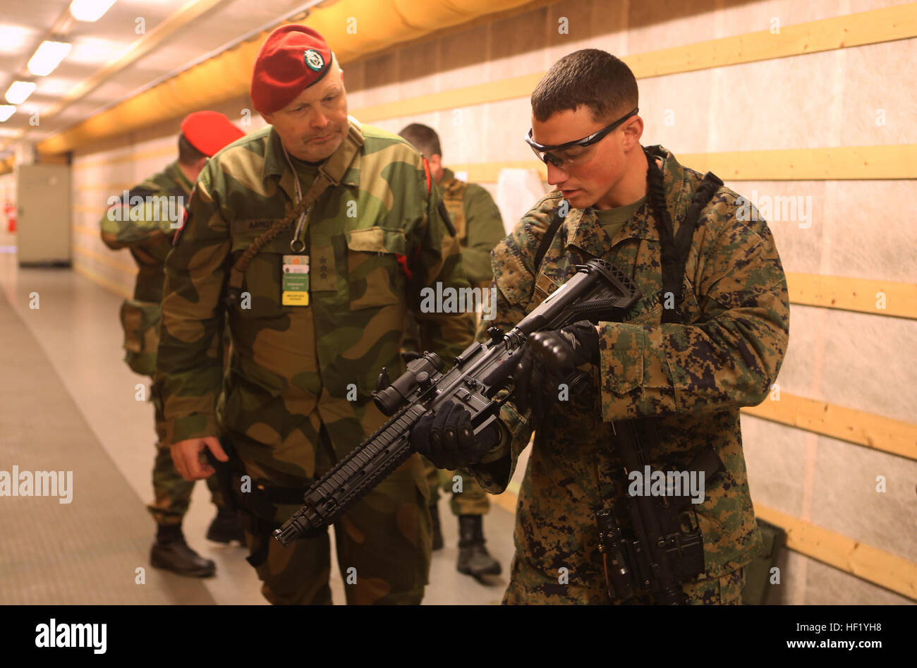 Sgt. James J. Cassidy (right), a military policeman with 2nd Supply Battalion, Combat Logistics Regiment 25, 2nd Marine Logistics Group, inspects an HK-416K assault rifle used by a Norwegian MP with Home Guard District 12 in an indoor firing range at Vaernes Garrison, Norway, Feb. 21, 2014. Two MPs attached to the battalion worked alongside their Norwegian counterparts with Home Guard District 12 to build stronger binds between the two nations' military forces. Cold Response 2014 is a Norwegian-led multinational exercise above the Arctic Circle designed prepare for crisis response operations.  Stock Photo