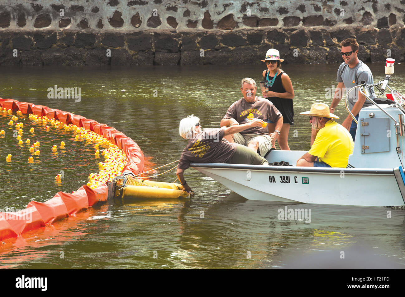 Race officials retrieve the first place rubber duckie from the Ala Wai Canal in Honolulu, during the United Cerebral Palsy Association of Hawaii's 27th Annual Great Hawaiian Rubber Duckie Race, March 21, 2014. While the majority of 3rd Battalion, 3rd Marine Regiment Marines train at the Mountain Warfare Training Center, in Bridgeport, Calif., Marines in the remain-behind element filled Ala Wai Canal with rubber duckies to support the annual event, which raises money to help people who have cerebral palsy. (U.S. Marine Corps photo by Lance Cpl. Matthew Bragg) The duck drops here, Marines volunt Stock Photo