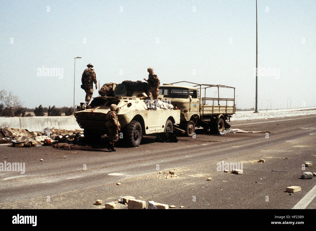 American servicemen examine an Iraqi BRDM-2 amphibious scout car captured during Operation Desert Storm.  An East German-made W-50 LA/A 4x4 truck is behind the scout car. Iraqi BRDM-2RKhb and IFA W50 captured by the coalition during Operation Desert Storm Stock Photo