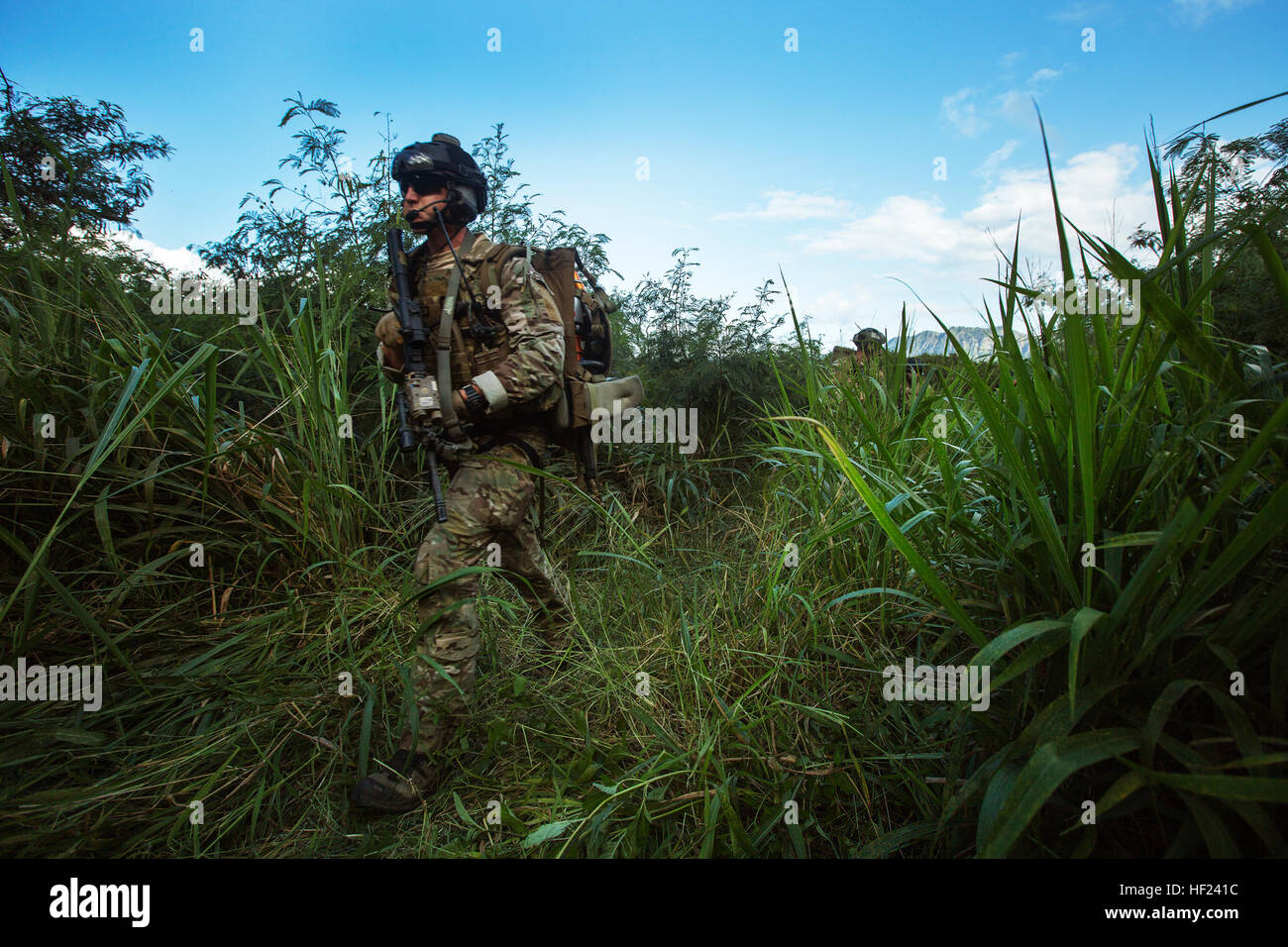 Air Force Pararescuemen with 131st Rescue Squadron, 129th Rescue Wing, Air National Guard, patrol through vegetation to reach the crash site of a downed aircraft during a search and rescue training mission at Marine Corps Training Area Bellows, Hawaii, April 28, 2014. The training mission involved 30 roleplayers participating as "villagers" while the Pararescuemen pulled two dummies, or "survivors," out of the aircraft and prepared them for a medical evacuation onto a Sikorsky HH-60G Pave Hawk helicopter. PJs are operatives tasked with the recovery and medical treatment of personnel in humanit Stock Photo