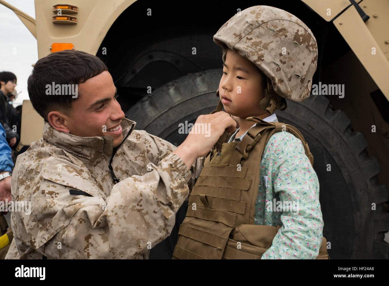 Cpl. Jose Escribano puts a Kevlar helmet onto a Japanese boy during Friendship Day at Marine Corps Air Station Iwakuni, Japan, May 5, 2014. Escrinao is a motor transportation operator with Marine Wing Support Squadron 171, and was just one of the many Marine that helped host more than 50,000 visitors. Friendship day is an event that allows Japanese citizens a chance to see military vehicles and aircraft, meet American service members, and get a taste of American culture. MCAS Iwakuni hosts Friendship Day 2014 140505-M-ZV462-013 Stock Photo
