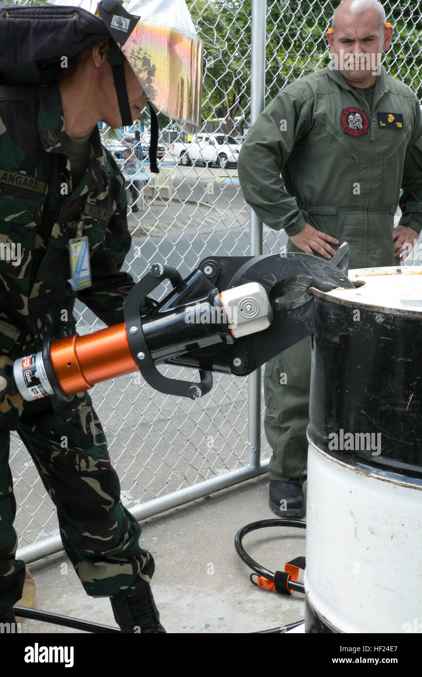 Philippine Air Force Tech. Sgt. Ronnie Angara uses shears, commonly known as the Jaws of Life, to cut into a barrel as U.S. Marine Corps Lance Cpl. David Landa observes during a Balikatan 2014 training event May 6, 2014, at Clark Air Base, Philippines. In its 30th year, Balikatan is an annual training exercise that strengthens the interoperability between the Armed Forces of the Philippines and U.S. military in their commitment to regional security and stability, humanitarian assistance and disaster relief. The training is part of a series of combined events aimed to improve the effectiveness  Stock Photo