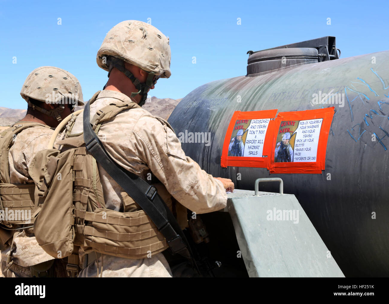 U.S. Marine Sgt. Ned Johnson and U.S. Sailor Hospitalman Apprentice Ricardo Lopez post 'Gunny Says' signs on a water buffalo to promote good hydration and cleanliness of the camp aboard Marine Corps Air Ground Combat Center, Twentynine Palms, Calif. during Exercise Desert Scimitar 14 on May 12, 2014. Desert Scimitar enables 1st Marine Division to test and refine its command and control capabilities by acting as the headquarters element for a forward-deployed Marine Expeditionary Force. (U.S. Marine Corps photo by Lance Cpl. Leah Agler, 1st Marine Division Combat Camera/Released) Desert Scimita Stock Photo