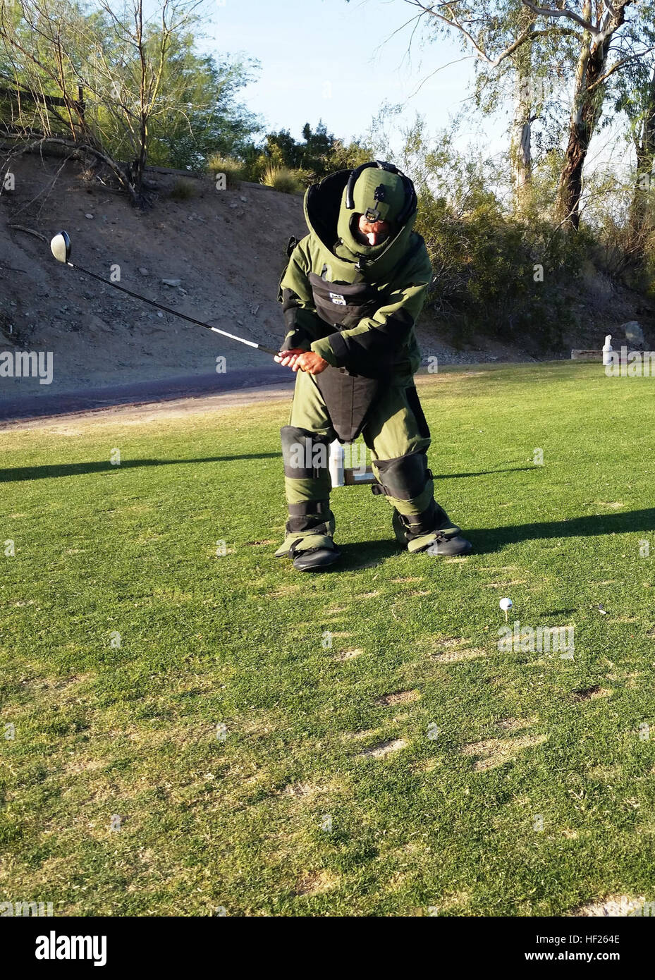 Marty Weibel takes a swing while wearing an Explosive Ordnance Disposal suit at Night-Ops V Charity Golf Tournament to benefit the Jared Allen's Homes for Wounded Warriors here May 17. Two dozen Guard members volunteered more than 200 personal hours setting up mock Army scenarios at six different golf holes for participants of the celebrity golf tournament to provide an example of the life of a Soldier. (National Guard photo by Army Sgt. Crystal Reidy) Guard volunteers take a swing at charity 140517-Z-ZZ999-011 Stock Photo