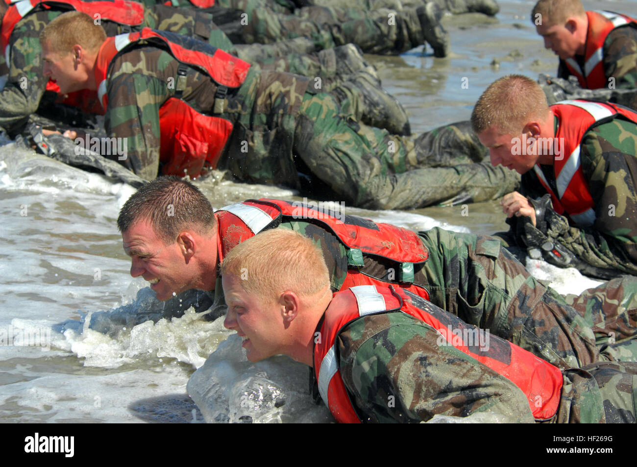 Basic crewman training students crawl through the surf during their