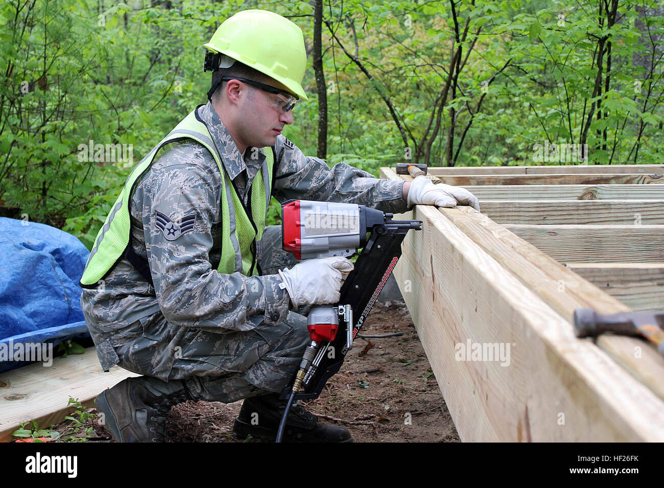Senior Airman Gydeon Burgess nails together the frame of a cabin while