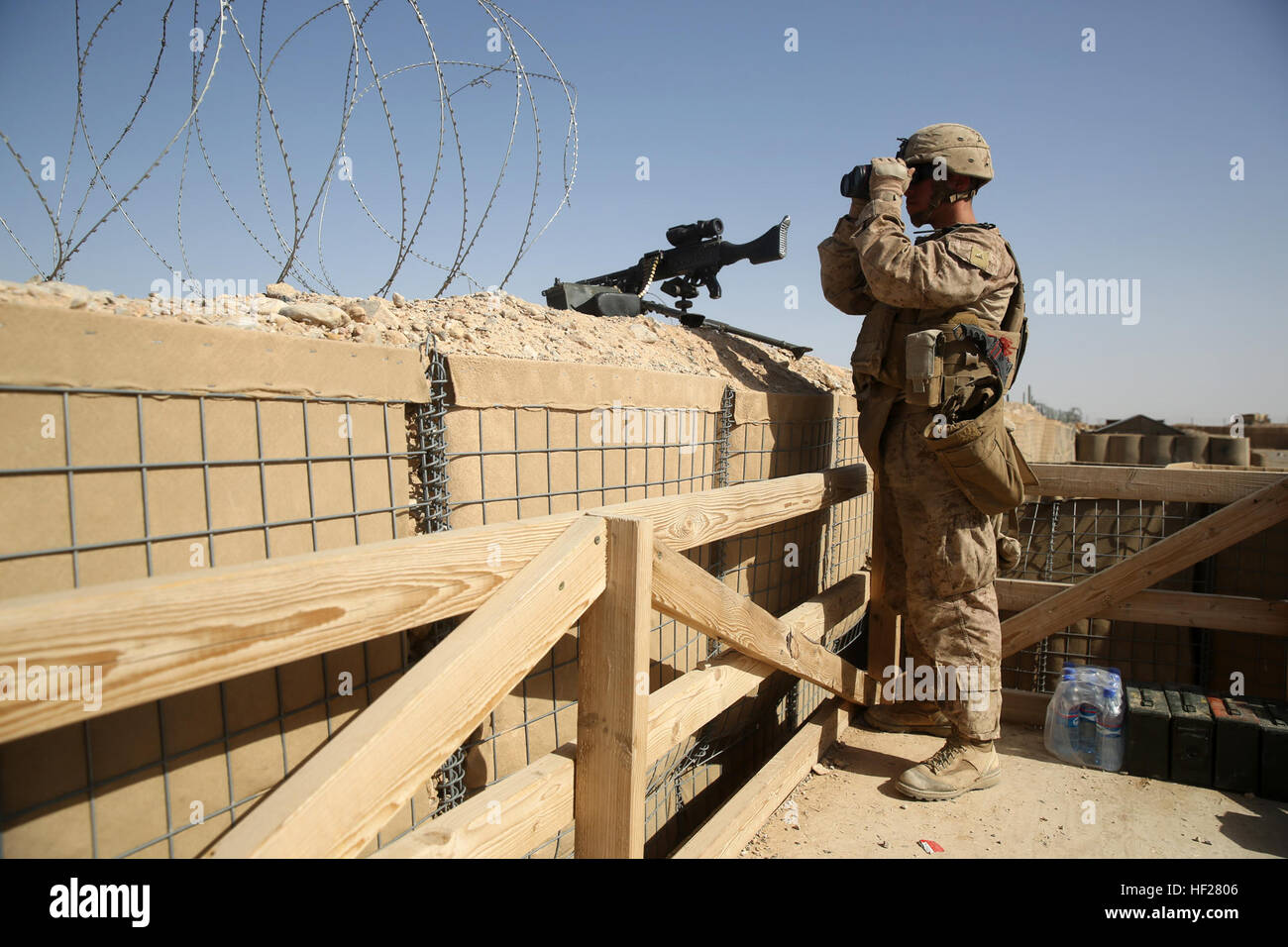 Lance Cpl. Hugo Morales, rifleman, Weapons Company, 1st Battalion, 7th Marine Regiment, scans the surrounding area with binoculars from a security post during a mission in Helmand province, Afghanistan, June 13, 2014. Morales, a native of El Paso, Texas, along with a platoon of infantrymen, provided security at Patrol Base Ouellette, an Afghan National Army controlled-base, during the Afghanistan presidential runoff elections. While International Security Assistance Force stood ready to support as needed, the elections were entirely Afghan led and Afghan conducted. Infantrymen stand by ready t Stock Photo