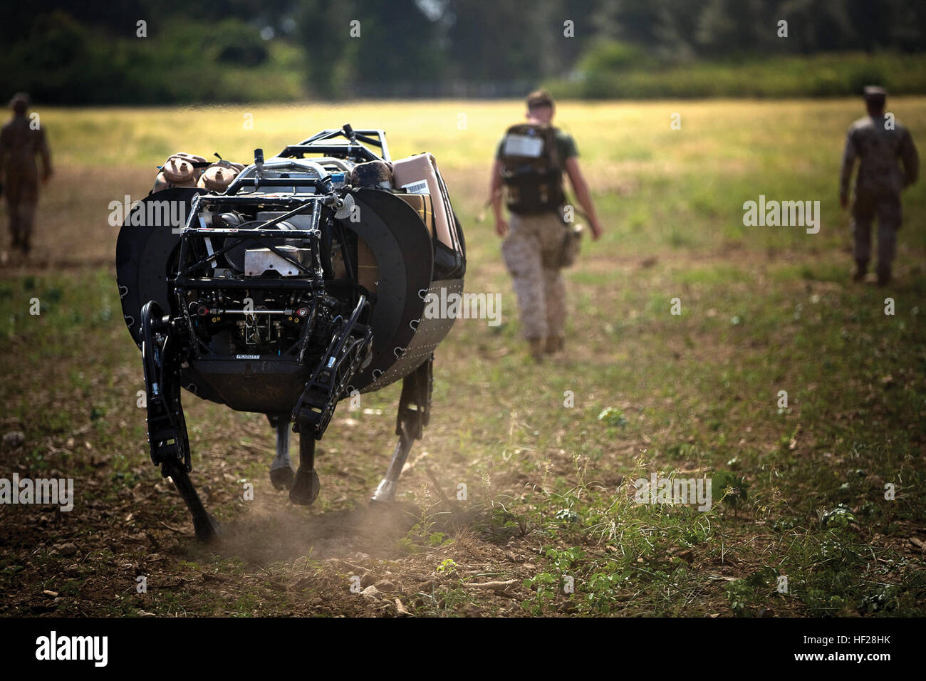 Lance Cpl. Timothy Knaggs (center), a team leader with India Company, 3rd Battalion, 3rd Marine Regiment, walks ahead of the Legged Squad Support System, acting as the "follow" for the machine at Marine Corps Training Area Bellows, Thursday. the LS3 is designed to carry Marine's supplies  like water, food and ammunition through rough terrain and is undergoing concept-based experimentation.  the Machine is operated with a Tactical Radio Control worn on the operators back. The LS3 operates in three modes; Joystick Mode allows for manual operation with a handheld controller; Go-To Mode, in which  Stock Photo