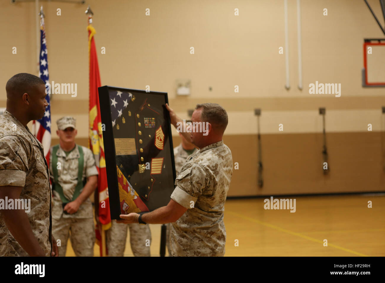 U.S. Marine Corps Master Sgt. Brown with Headquarters and Support Battalion, School of Infantry-East (SOI-E), presents Master Gunnery Sgt. James G. Corwin with a shadow box during his retirement ceremony aboard Camp Geiger, N.C., July, 9, 2014. Marines with SOI-E, along with family and friends, gathered to celebrate Corwin's retirement from the Marine Corps after serving 26 faithful years. (U.S. Marine Corps photo by Cpl. Maricela Meza/Released) MGySgt Corwin retirement 140709-M-AX605-099 Stock Photo
