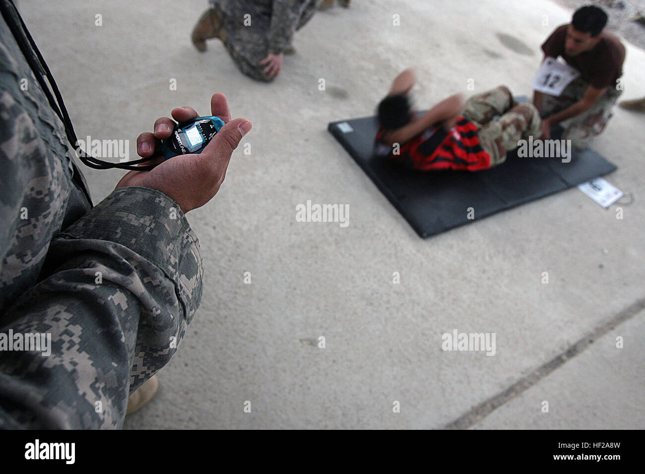 Iraqi Army noncommissioned officers perform the sit-up portion of the U.S. Army physical fitness test during the “Iraqi Army NCO and Soldier of the Year” competition here Oct. 16. Competitors awoke early first to complete an Army physical fitness test; sit-ups, push-ups and a 2-mile run, all timed. The soldiers then strapped on their Kevlar helmets and flak vests, slung their rifles, and took off on a six-kilometer run to the rifle range. No sooner did they reach the finish line then they broke into groups, loaded their rifles, and shot the Iraqi Army marksmanship test; five rounds in the pron Stock Photo