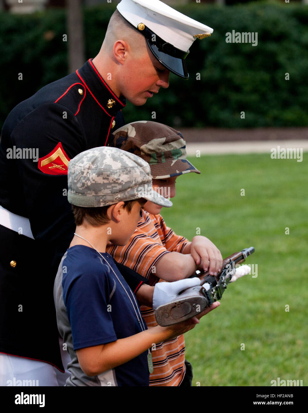 A U.S. Marine lance corporal shows his ceremonial M1 Garand rifle to young children during an Evening Parade reception at Marine Barracks Washington in Washington, D.C., July 18, 2014. Evening Parades are held every Friday during the summer months. (U.S. Marine Corps photo by Lance Cpl. Jacob Bozic/Released) Evening Parade 140718-M-GR671-063 Stock Photo