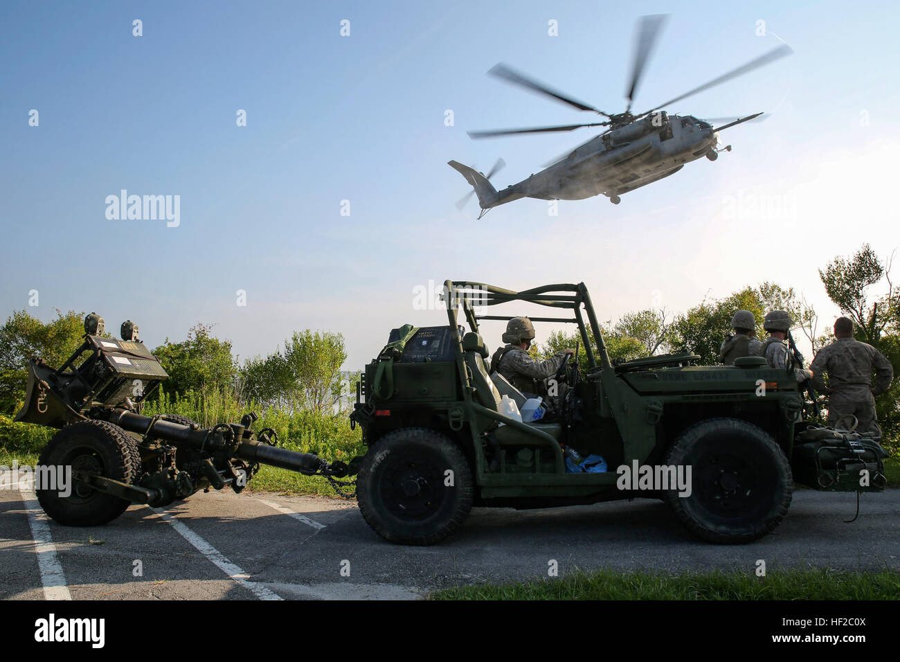 Marines with 2nd Battalion, 10th Marine Regiment, 2nd Marine Division, watch a CH-53E Super Stallion helicopter land while waiting to load their Expeditionary Fire Support Systems to conduct an aerial-raid mission aboard Marine Corps Base Camp Lejeune, North Carolina, July 30, 2014.  The EFSS consists of an Internally Transportable-Strike Vehicle with a 120 mm mortar in tow, providing mobile fire support that bridges the gap between 81 mm mortars and the 155 mm cannons.  (U.S. Marine Corps photo taken by Lance Cpl. Alex W. Mitchell/released) EFSS teams conduct amphibious assaults, aerial raid  Stock Photo