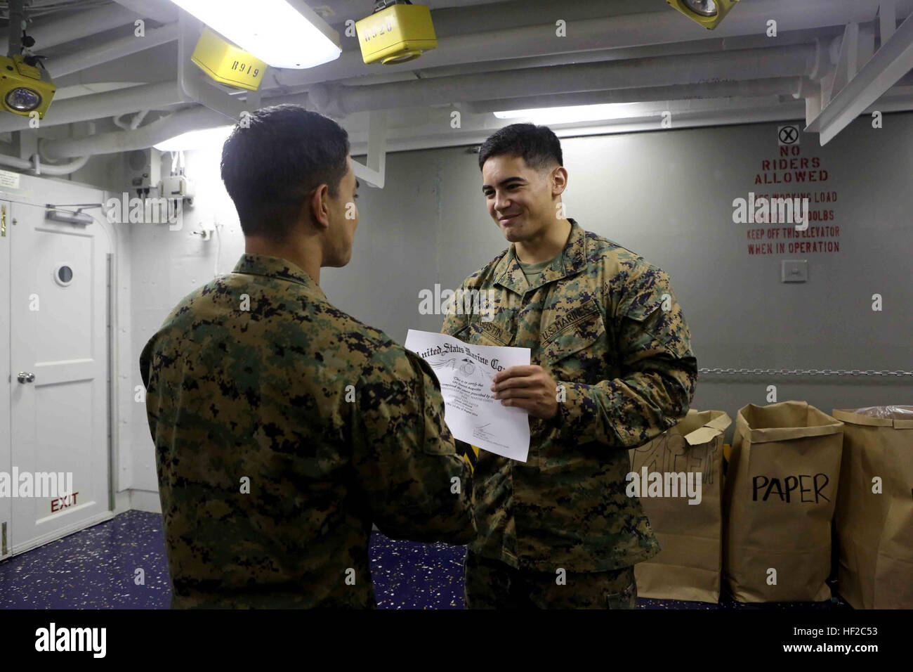 Corporal Daniel Agustin, a landing support specialist with Special Purpose Marine Air Ground Task Force South, and a native of Seattle, is presented his certificate of completion for a combat lifesaver course aboard the future amphibious assault ship USS America (LHA 6), Aug. 1, 2014. The Marines were taught several different lifesaving techniques over a three-day period, and were tested during a final exercise in order to receive their certification. Certified Combat lifesavers are trained to provide initial medical aid for their unit in combat situations. The Marines who received their certi Stock Photo