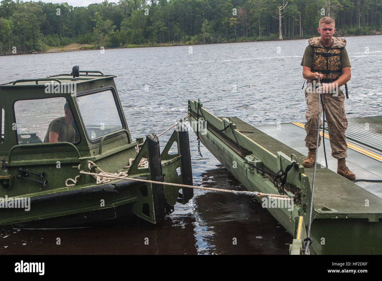 A U.S. Marine with Bridge Company (Bridge Co.), 8th Engineer Support Battalion, 2nd Marine Logistics Group, pulls in an interior bay during improved ribbon bridging training on Camp Lejeune, N.C., August 11, 2014. Bridge Co. Marines used the bays to put together a continuous span that touched shore to shore for 2nd Tanks Battalion to cross using M1A1 Abrams Main Battle Tanks. (U.S. Marine Corps photo by Lance Cpl. Desir M. Mora/Released) Bridge Company Marines conduct training with 2nd Tanks Battalion 140811-M-TG562-437 Stock Photo