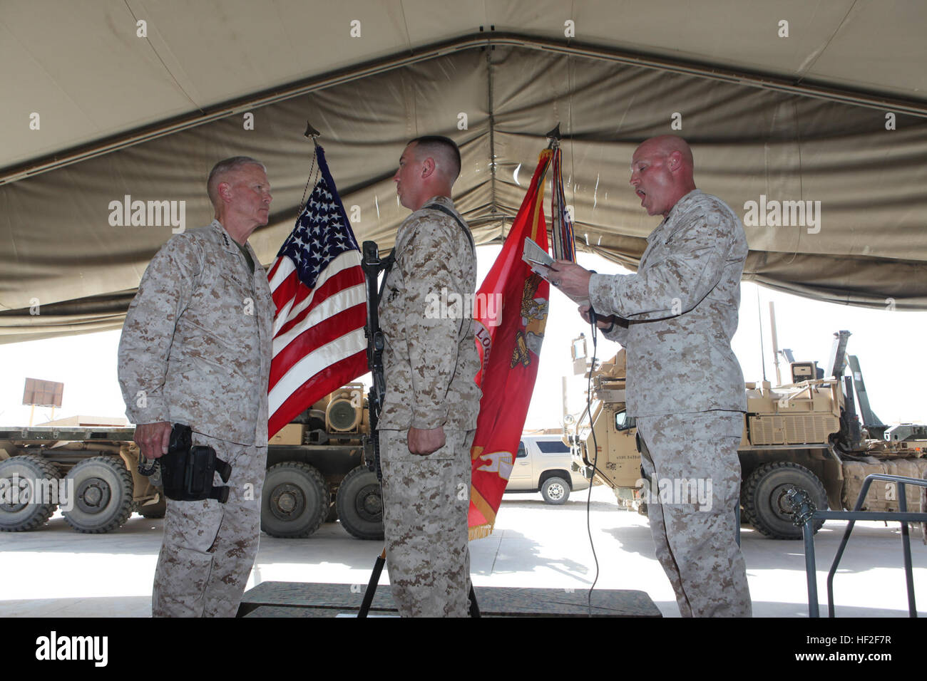 Sergeant Maj. Micheal Barrett, right, the 17th Sergeant Major of the Marine Corps, reads the meritorious promotion warrant of Lance Cpl. William Gelroth, center, a radio repair technician with Intermediate Maintenance Activity Platoon, Combat Logistics Battalion 1, during his meritorious promotion ceremony aboard Camp Leatherneck, Afghanistan, Sept. 6, 2014. General James F. Amos, the 35th Commandant of the Marine Corps, meritoriously promoted Gelroth, a native of Louviers, Colo., to the rank of corporal during his final visit to Helmand province. Commandant, Sergeant Major of the Marine Corps Stock Photo