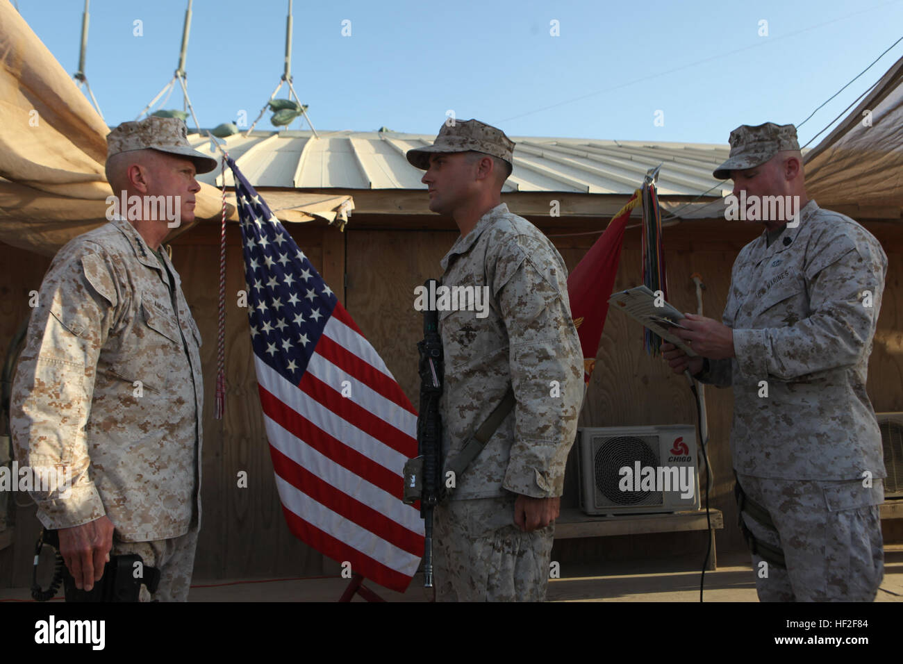 Sergeant Maj. Micheal Barrett, right, the 17th Sergeant Major of the Marine Corps, reads the meritorious promotion warrant of Corporal Dominic Sharpsteensurina, an assault section leader with Charley Company, 1st Battalion, 7th Marine Regiment, during his meritorious promotion ceremony aboard Camp Leatherneck, Afghanistan, Sept. 6, 2014. General James F. Amos, the 35th Commandant of the Marine Corps, meritoriously promoted Sharpsteensurina, a native of Minneapolis, to the rank of sergeant during his final visit to Helmand province. Commandant, Sergeant Major of the Marine Corps visit Marines,  Stock Photo