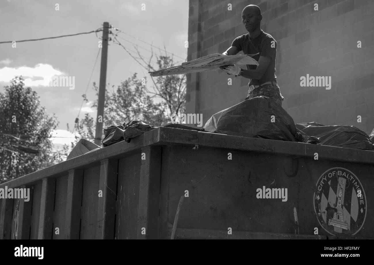Navy Lt. Marufudeen Oladipupo, an assistant supply officer with the USS Leyte Gulf, and a New York City native, packs trash on top of a dumpster in an alleyway behind the Great Blacks in Wax Museum in Baltimore on Sept. 12, 2014. More than 60 U.S. Marines and sailors from the United States, Canada, Germany, and Turkey were called upon to help restore the ship. The Marines, from various units, including II Marine Expeditionary Force, 1st Battalion, 10th Marine Regiment, 2nd Marine Division, and 2nd Marine Logistics Group based at Marine Corps Base Camp Lejeune, N.C., and Marine Heavy Helicopter Stock Photo