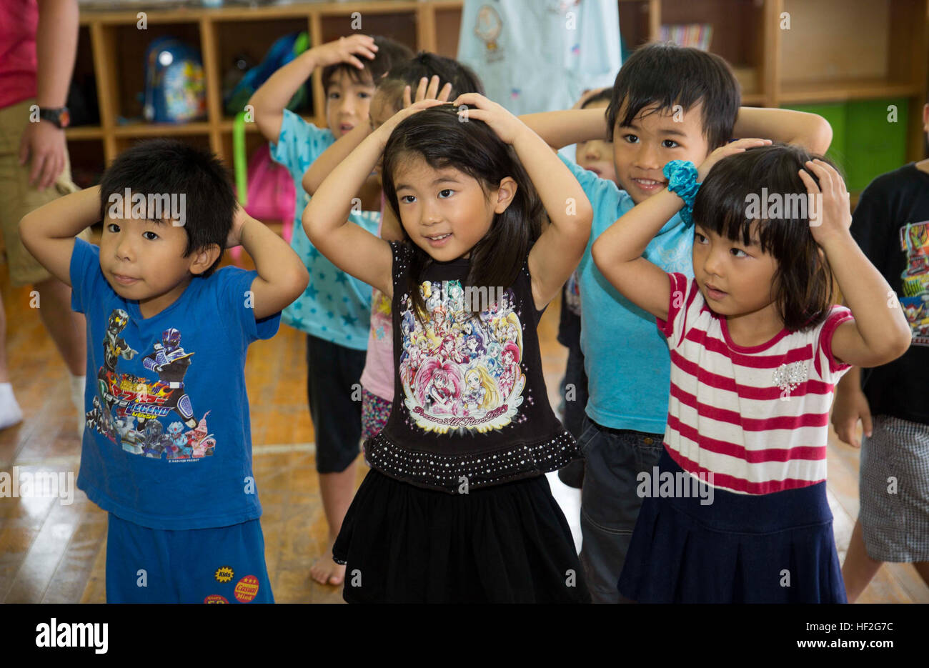 Preschool students and Marines dance and sing to “Head, Shoulders, Knees and Toes” during the “Play in English” program Sept. 19 at Namisato Nursery in Kin Town. While volunteering at the local school, Marines also played a game of musical chairs and taught basic English phrases and expressions. The Marines are with 5th Air Naval Gunfire Liaison Company, III Marine Expeditionary Force Headquarters Group, III MEF. (U.S. Marine Corps photo by Lance Cpl. Diamond N. Peden/Released) Marines teach English to Okinawa students through song, play during new program 140919-M-PJ295-342 Stock Photo