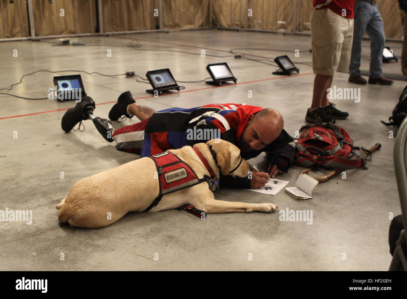 Sgt. Andres Burgos, a native of Orlando, Florida, gets some assistance analyzing his shots from his service dog, Gunny, during shooting practice for the Marine team, Sept. 21, in preparation for the 2014 Warrior Games. The Marine team has been training since Sept. 15 in order to build team cohesion and acclimate to the above 6,000 feet altitude of Colorado Springs. The Marine team is comprised of both active duty and veteran wounded, ill and injured Marines who are attached to or supported by the Wounded Warrior Regiment, the official unit of the Marine Corps charged with providing comprehensi Stock Photo