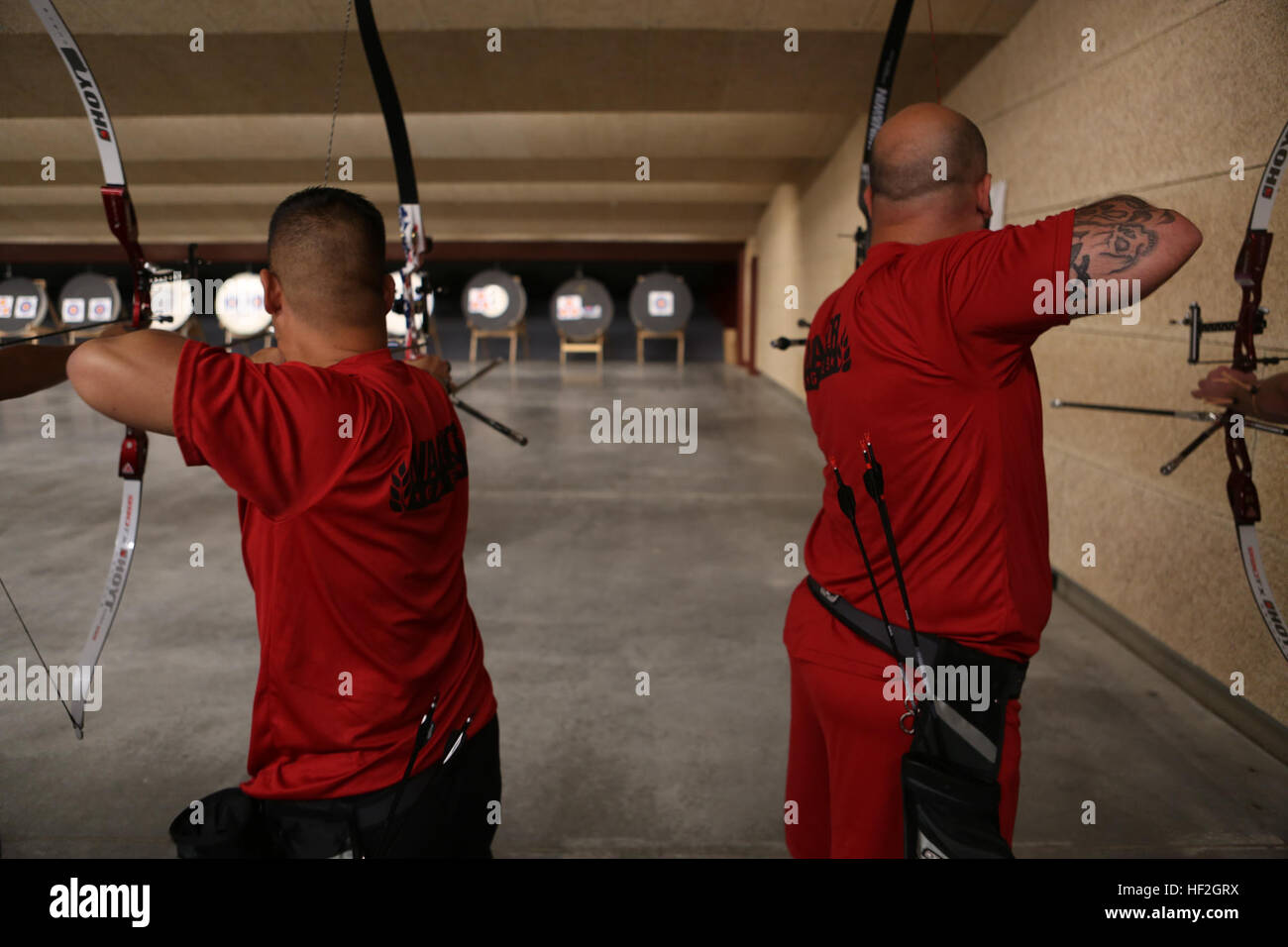 Capt. Chris McGleinnaiss, from Kailua, Hawaii, and teammate Sgt. Andres Burgos, from Orlando, Florida, draw back and prepare to release arrows during archery practice for the Marine team, September 25, in preparation for the 2014 Warrior Games. The Marine team has been training since September 15 in order to build team cohesion and acclimate to the above 6,000 ft. altitude of Colorado Springs.  The Marine team is comprised of both active duty and veteran wounded, ill and injured Marines who are attached to or supported by the Wounded Warrior Regiment, the official unit of the Marine Corps char Stock Photo