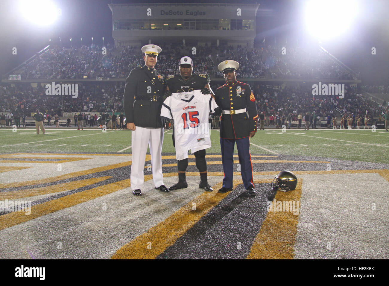 Bryce English, a defensive tackle from Desoto High School selected to play in the 2015 Semper Fidelis All-American Bowl, receives his jersey from Maj. Charles Nicol (left), the commanding officer of Recruiting Station Dallas, and Sgt. Timothy Clark (right), a recruiter with Recruiting Substation Dallas South, during the halftime ceremony of the Desoto vs. Cedar Hill High School football game Oct. 23. The United States Marine Corps is recognizing exemplary student athletes across the country through the Semper Fi Bowl. Now in its fourth year, the game will feature approximately 100 student athl Stock Photo