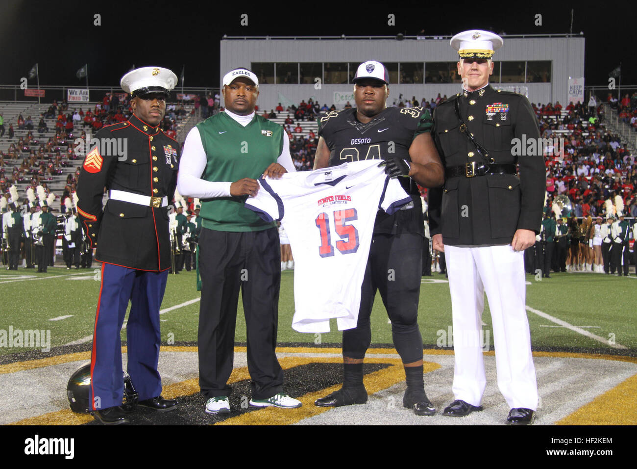Bryce English, a defensive tackle from Desoto High School selected to play in the 2015 Semper Fidelis All-American Bowl, alongside Claude Mathis, Desoto High School Head Football Coach, receives his jersey from Maj. Charles Nicol (right), the commanding officer of Recruiting Station Dallas, and Sgt. Timothy Clark (left), a recruiter with Recruiting Substation Dallas South, during the halftime ceremony of the Desoto vs. Cedar Hill High School football game Oct. 23. The United States Marine Corps is recognizing exemplary student athletes across the country through the Semper Fi Bowl. Now in its  Stock Photo