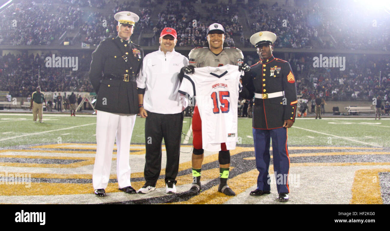 Richard Moore, a linebacker from Cedar Hill High School selected to play in the 2015 Semper Fidelis All-American Bowl, alongside Joey McGuire, Cedar Hill High School Head Football Coach, receives his jersey from Maj. Charles Nicol (left), the commanding officer of Recruiting Station Dallas, and Sgt. Timothy Clark (right), a recruiter with Recruiting Substation Dallas South, during the halftime ceremony of the Desoto vs. Cedar Hill High School football game Oct. 23. The United States Marine Corps is recognizing exemplary student athletes across the country through the Semper Fi Bowl. Now in its Stock Photo