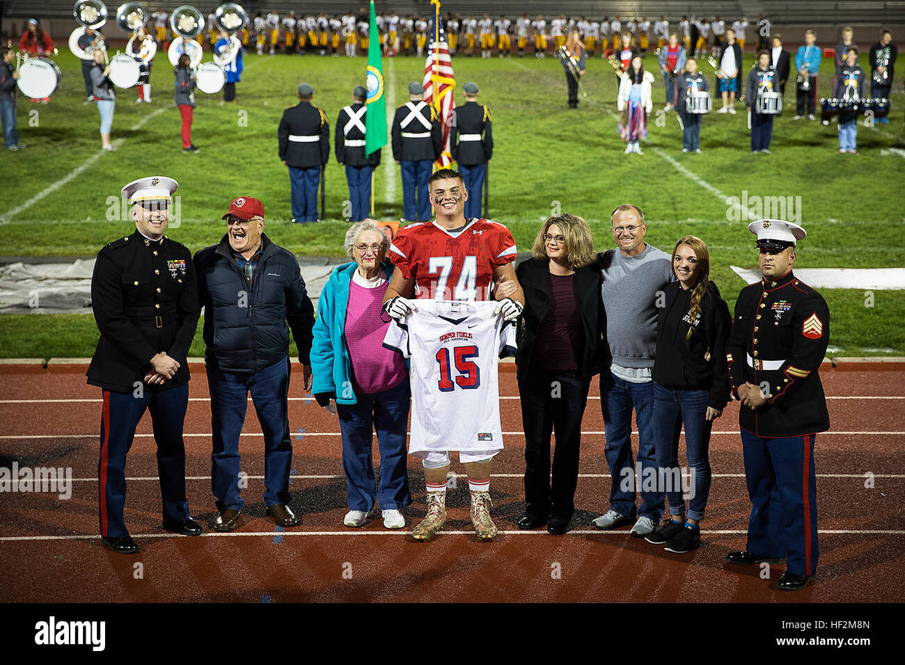 Shane Lemieux (center), a offensive tackle for the West Valley High School Rams varsity football team and 17-year-old native of Yakima, Wash., stands among his family members after receiving his 2015 Semper Fidelis All-American Bowl jersey from Capt. Ryan Sahlberg (left), the operations officer of Marine Corps Recruiting Station Seattle, and Sgt. James Campos, a local Marine recruiter, at a game against the Wenatchee High School Panthers at West Valley High School in Yakima, Wash., Oct. 31, 2014. Lemieux, a University of Oregon commit, is among approximately 100 student athletes from across th Stock Photo