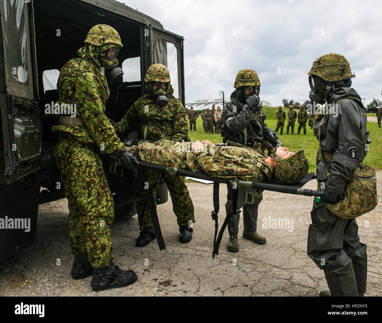 Japan Ground Self-Defense Force members with the Special Weapons Protection Unit unload a casualty during a response exercise Dec. 1 at Camp Naha, Okinawa. The training increased ties between the JGSDF and participating U.S. Marines by building trust and confidence between the two nations. The JGSDF members are with the Nuclear Biological Chemical Unit, 15th Brigade. (U.S. Marine Corps photo by Lance Cpl. Tyler S. Giguere/Released) Marines, JGSDF rapidly respond to simulated contaminations 141202-M-RZ020-004 Stock Photo