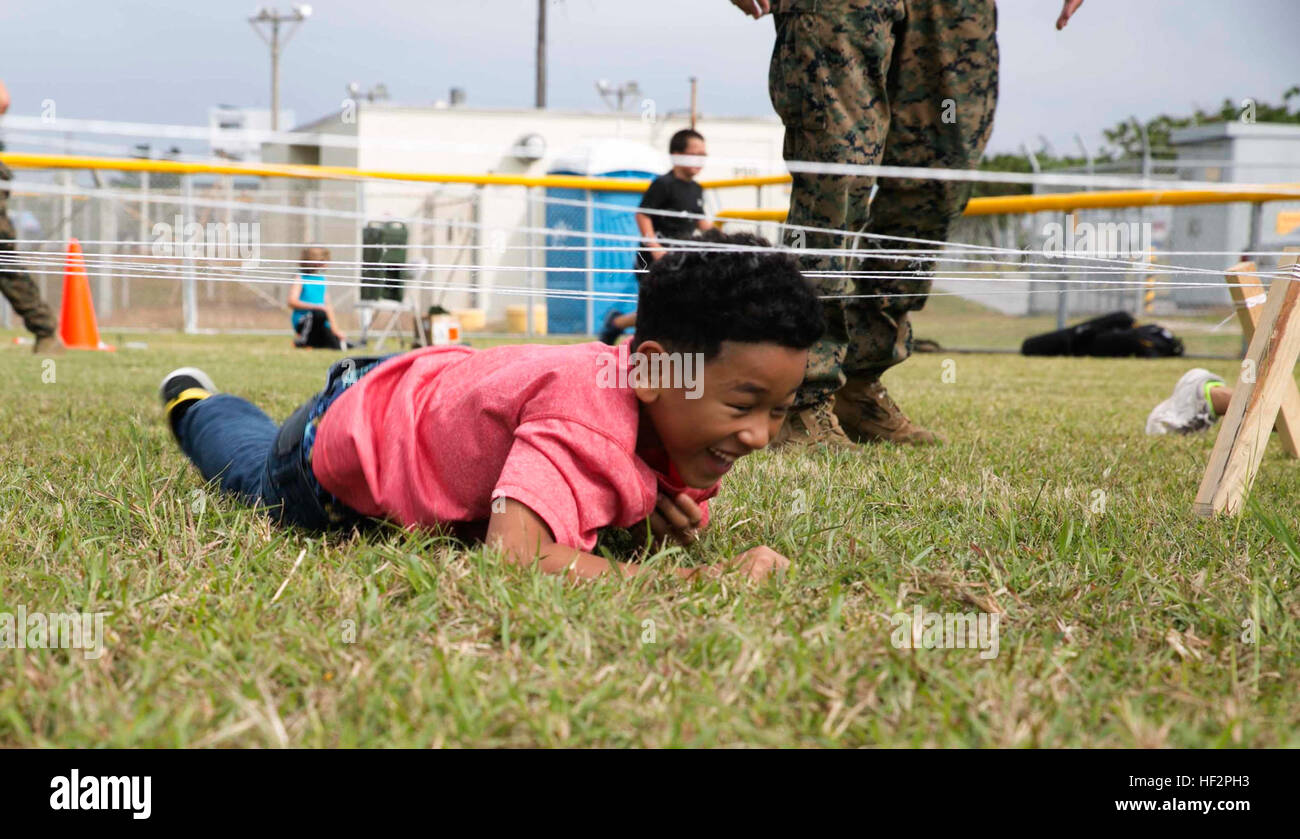 Anthony Louis, a student at Kinser Elementary School, crawls under string that simulates barbed wire Dec. 10 during a Warrior Day on Camp Kinser. “The purpose of Warrior Day is to provide the children of Kinser Elementary School an opportunity to conduct training similar to what their parents do,” said Staff Sgt. Tracie Mahan, a machinist with 3rd Maintenance Battalion, Combat Logistics Regiment 35, 3rd Marine Logistics Group, III Marine Expeditionary Force. (U.S. Marine Corps Photo by Cpl. Thor J. Larson/Released) Warrior Day teaches children about parentsE28099 life in Marine Corps 141210-M- Stock Photo
