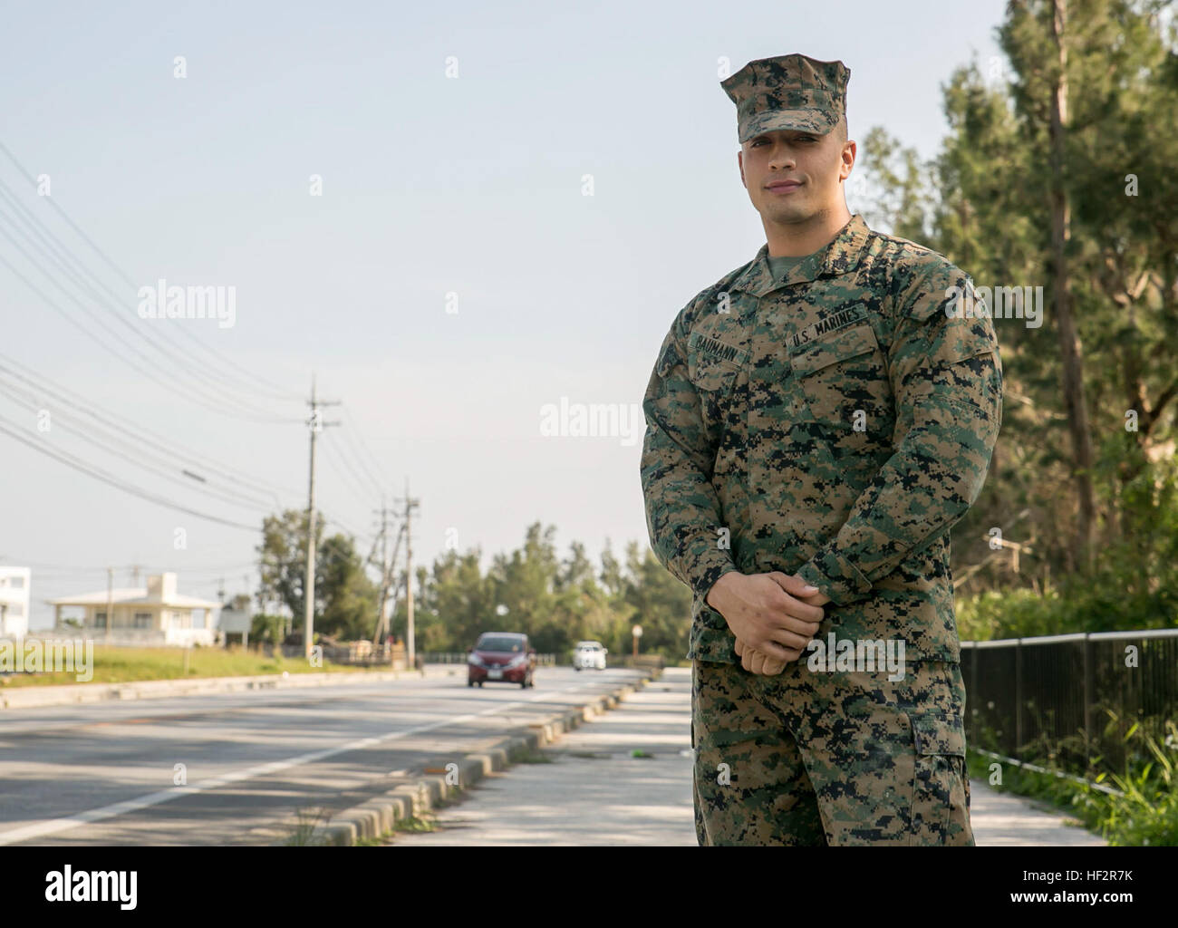 Sgt. Jacob Baumann poses for a photo near the scene where he saved a local elderly man after he fell off of his bicycle onto the road. Baumann moved the local and his bike to the side and began several chest compressions that saved his life. “It was more reaction from my training and just what Marines do, said Baumann. “It was more on the lines of, ‘what can I do to help?’ That’s what we’re here for as Marines; we’re here to help.” Baumann is a fire support man with Headquarters Battery, 12th Marine Regiment, 3rd Marine Division, III Marine Expeditionary Force. (U.S. Marine photo by Cpl. Rebec Stock Photo