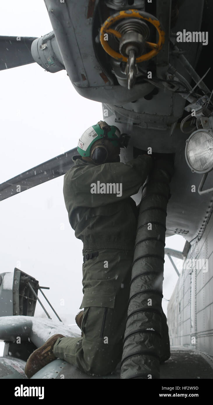 Sergeant Caleb Davis, a helicopter airframe mechanic with Marine Heavy Helicopter Squadron 464, runs a hose from a preheater to one of the engines on a CH-53 Super Stallion during a deployment for training exercise aboard Camp Dawson, W. Va., Jan. 30, 2015. The squadron used preheaters to warm up the helicopters because of the heavy snow and ice at Camp Dawson. HMH-464 battle cold weather during DFT 150130-M-FD819-538 Stock Photo