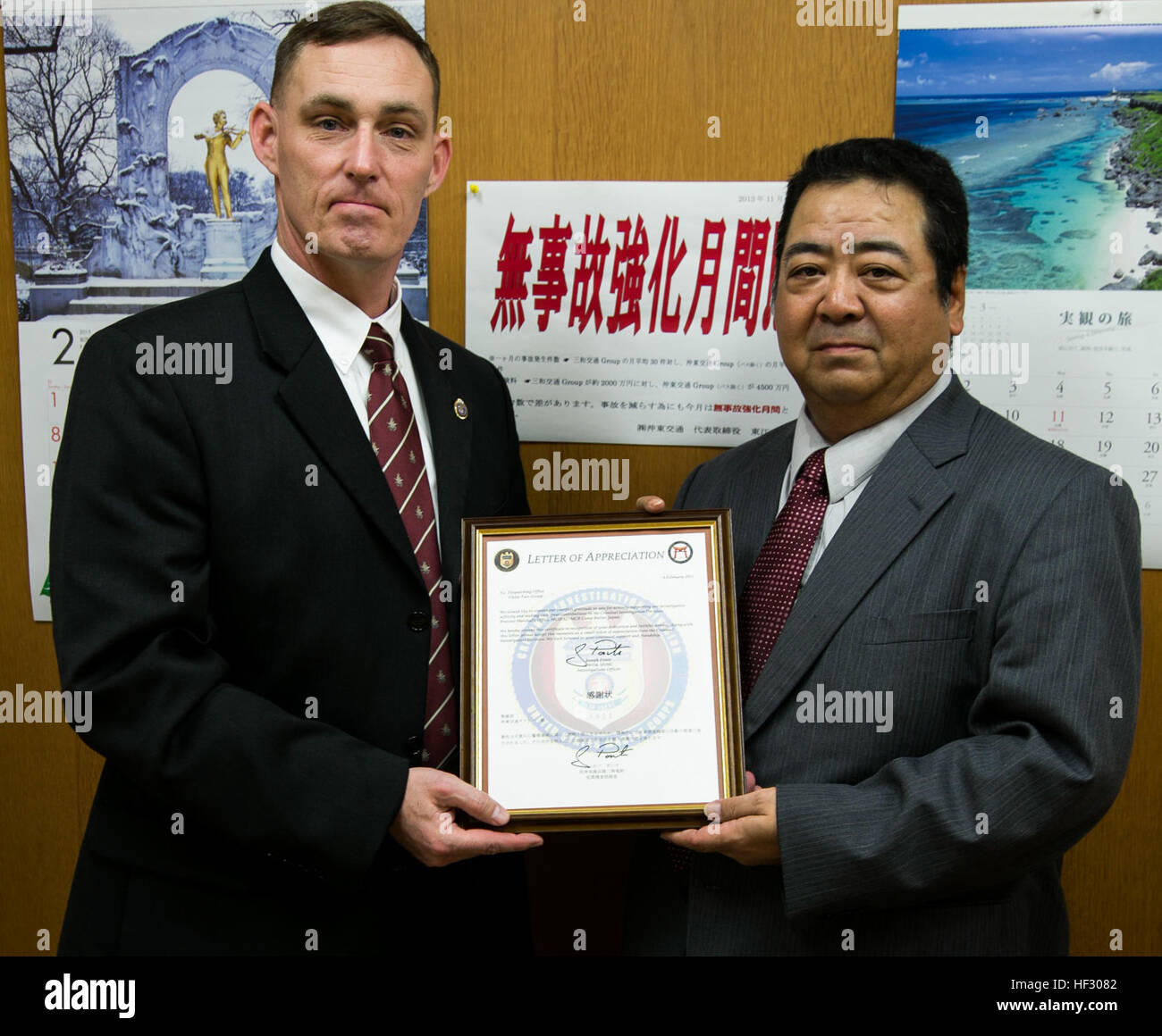 U.S. Marine Chief Warrant Officer Joseph Ponte, left, poses alongside Kazunari Agarie with the letter of appreciation awarded to Okito Taxi Company Feb. 24 during a visit to Okito Taxi Company in Urasoe City, Okinawa. The Okito Taxi Company, contracted with the Army and Air Force Exchange Service, was recognized not only for their efforts in solving a credit card fraud case, but also turning in items left in taxis by service members. “In law enforcement, we rely on many different relationships with people who may have information to help us solve our investigations,” said Ponte, a native of Po Stock Photo