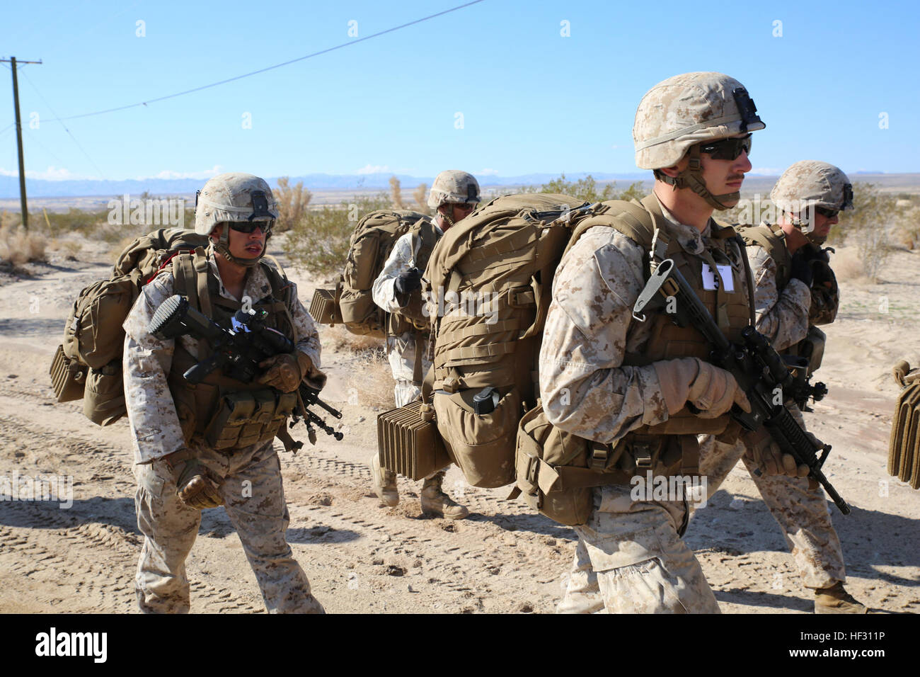 Marines with Company A, Ground Combat Element Integrated Task Force, conduct a 7-Kilometer hike to the defense during a pilot test at Range 110, Marine Corps Air Ground Combat Center Twentynine Palms, California, March 3, 2015, in preparation for the Marine Corps Operational Test and Evaluation Activity assessment. From October 2014 to July 2015, the GCEITF will conduct individual and collective level skills training in designated ground combat arms occupational specialties in order to facilitate the standards-based assessment of the physical performance of Marines in a simulated operating env Stock Photo