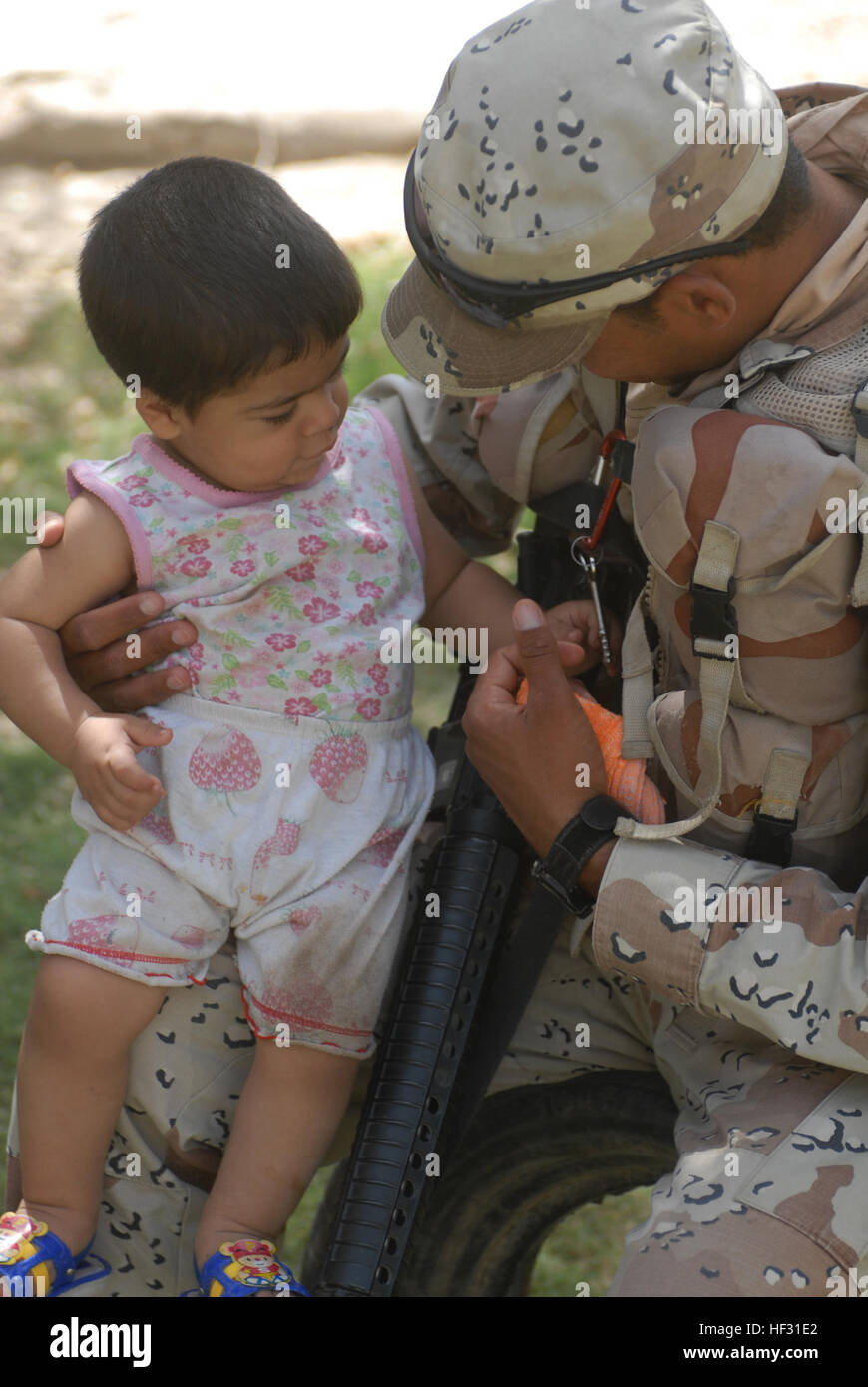 An Iraqi soldier with the 6th Iraqi army entertains an Iraqi child with a set of keys in Abu Ghraib, Iraq, on June 10. Flickr - DVIDSHUB - Patrol in Abu Ghraib Stock Photo