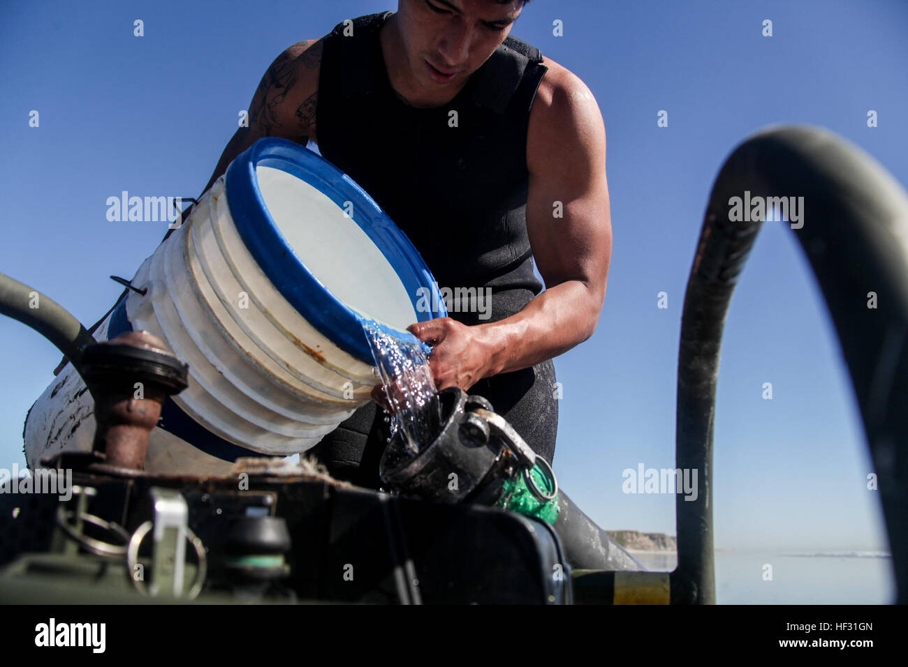 U.S. Marine Lance Cpl. Fransisco pours ocean water into a water