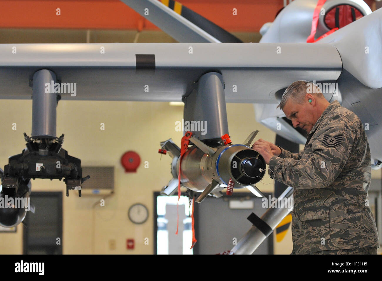 Members of the 174th Attack Wing Munitions Flight train on loading procedures on March 7, 2015, at Hancock Field Air National Guard Base. The munition load crew must be certified quarterly on transporting, loading and wiring munitions onto the MQ-9 Reaper that precisely hit specific targets. The MQ-9 Reaper is an armed, multi-mission, medium-altitude, long-endurance remotely piloted aircraft that is employed primarily for intelligence, surveillance and reconnaissance (ISR). Military intelligence is a military discipline that collects information and analysis to provide guidance and direction t Stock Photo