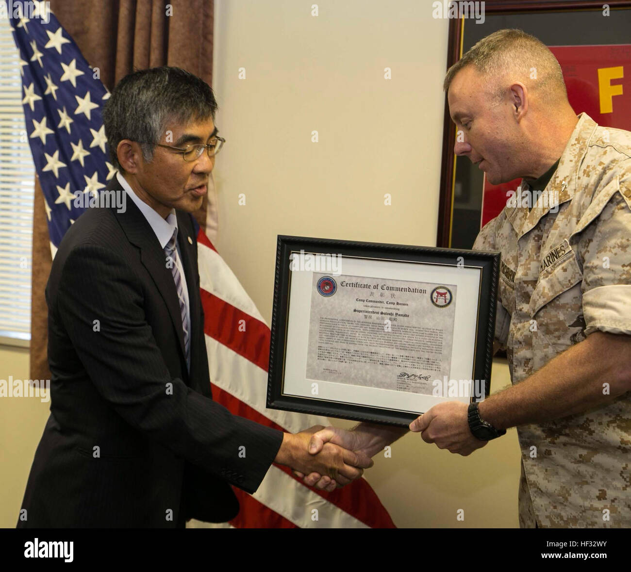 Col. Sean M. McBride, right, presents a certificate of commendation March 12 at Camp Hansen to Satoshi Yamada, the Ishikawa chief of police, for his actions on duty. Yamada is retiring as the police chief after two years. Yamada worked with III Marine Expeditionary Force by helping with disaster relief, anti-terrorism and evacuation drills, the drunken driving campaign and spoke at the welcome aboard seminars for Marines on the Unit Deployment Program. Yamada is from Naha City, Okinawa. McBride is from Butte, Montana, and is the commanding officer for III Marine Expeditionary Force Headquarter Stock Photo