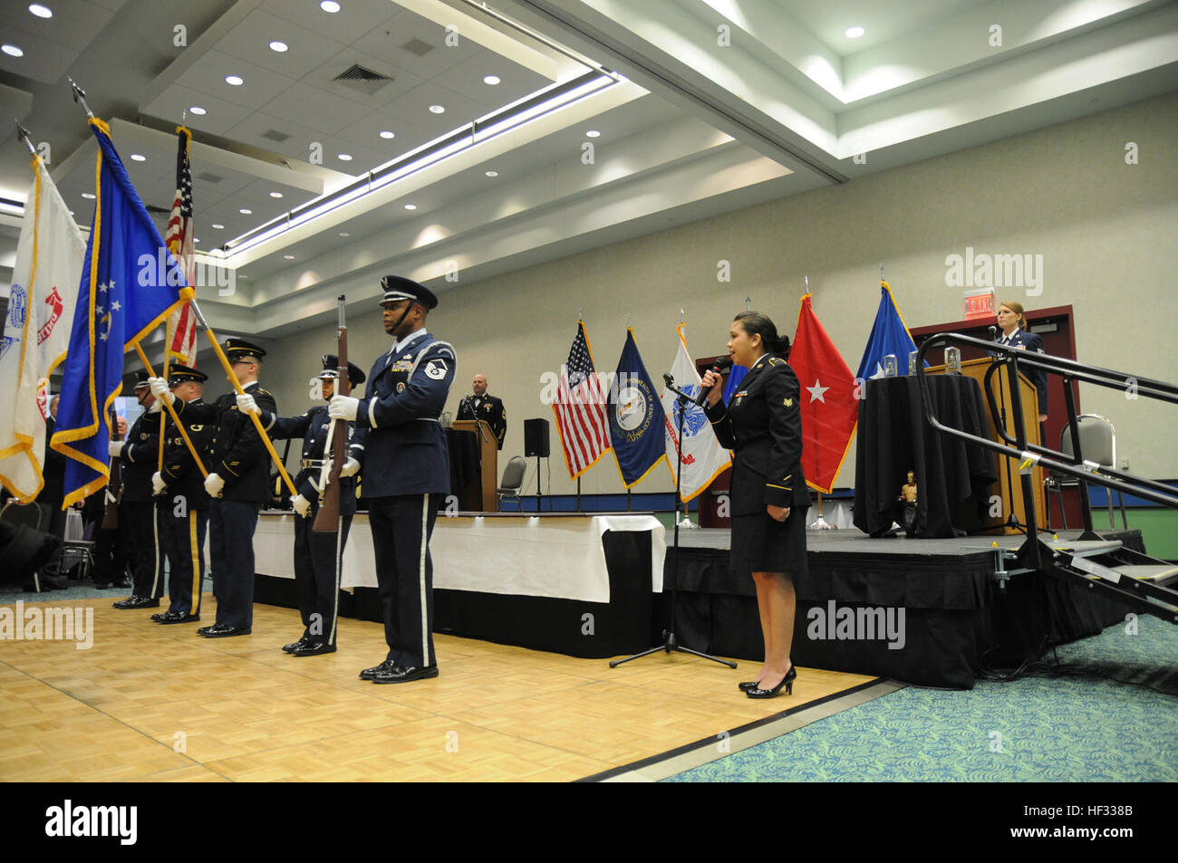Kentucky Army National Guard Spc. Stacy Pesut, a human resources specialist assigned to Headquarters and Headquarters Detachment, 103rd Chemical Battalion, sings the national anthem, while the joint-service Kentucky National Guard color guard presents the colors at the 2015 Outstanding Airman and Soldier of the Year banquet, March 14, at the Kentucky Fair and Exposition Center in Louisville, Kentucky. The annual awards dinner honors Kentucky's finest Airmen and Soldiers who are recognized by their peers for dedicating themselves to the welfare and security of our nation. (Photo by Sgt. 1st Cla Stock Photo