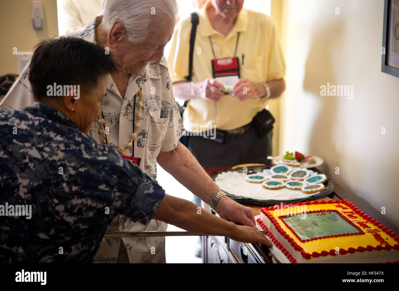 Rear Admiral Bette Bolivar, commander of Joint Region Marinas, and retired Lt. Gen. Lawrence Snowden cut a cake with a ceremonial sword during a luncheon at the admiral's home. The veterans stopped on top of Nimitz Hill for a quick lunch, refreshments and a slice of cake during their tour visiting war memorials and battle sites. The group then traveled to Iwo Jima, now known officially as Ioto, commemorating the 70th anniversary of the Battle of Iwo Jima. (U.S. Marine Corps photo by Lance Cpl. Jacob Snouffer/Released) Iwo Jima veterans luncheon 150319-M-WW824-201 Stock Photo